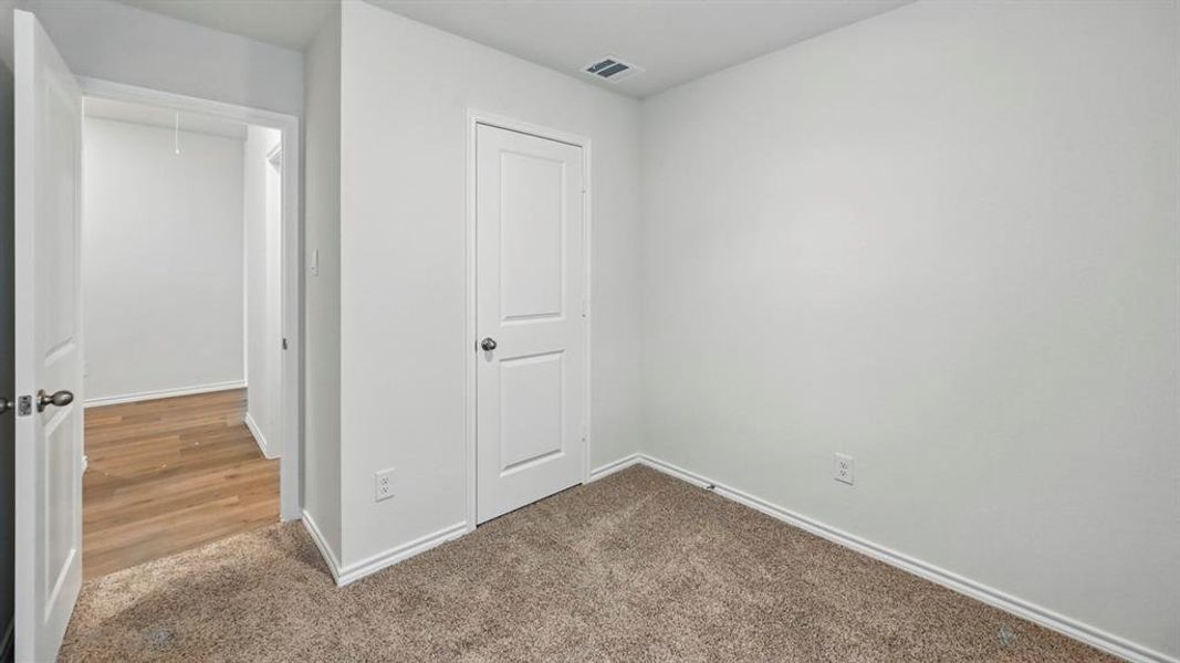 Unfurnished bedroom featuring dark carpet and attic access Unfurnished bedroom featuring dark carpet and attic access