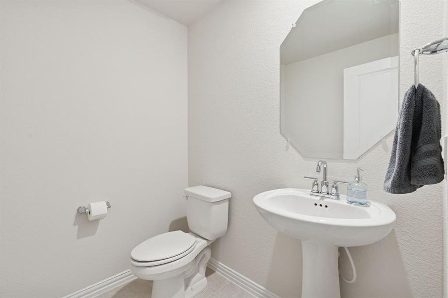 Half bathroom with light tile patterned floors and a textured wall