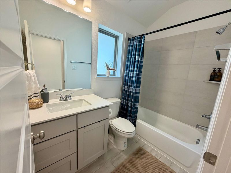 Modern bathroom featuring a sleek vanity with ample storage, a polished countertop, and a bathtub with stylish tile surround.