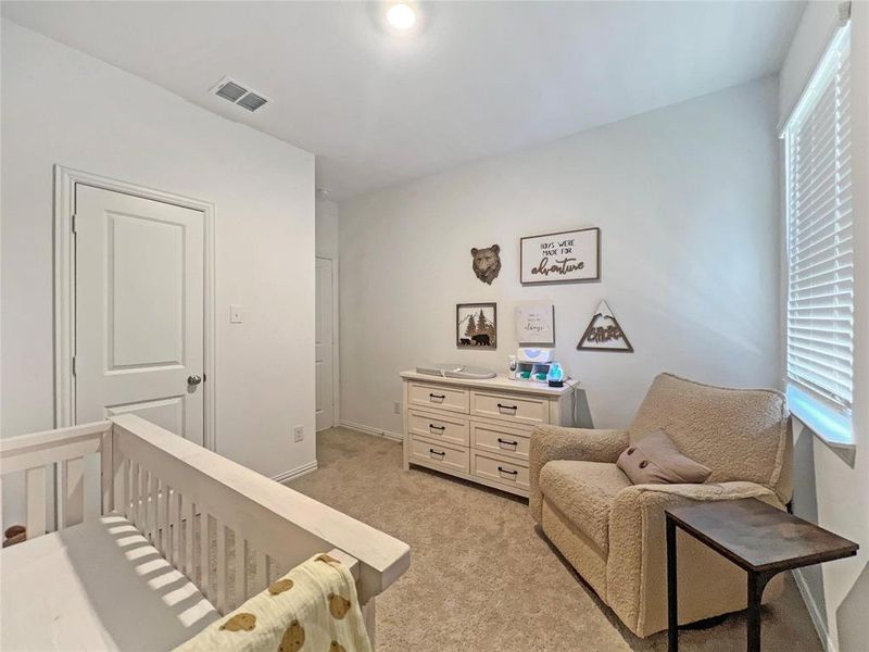 Bedroom featuring light colored carpet and a nursery area