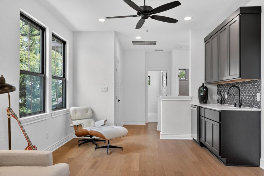 Natural wood flooring complements this living area with a convenient wet bar and ample daylight. Natural wood flooring complements this living area with a convenient wet bar and ample daylight.