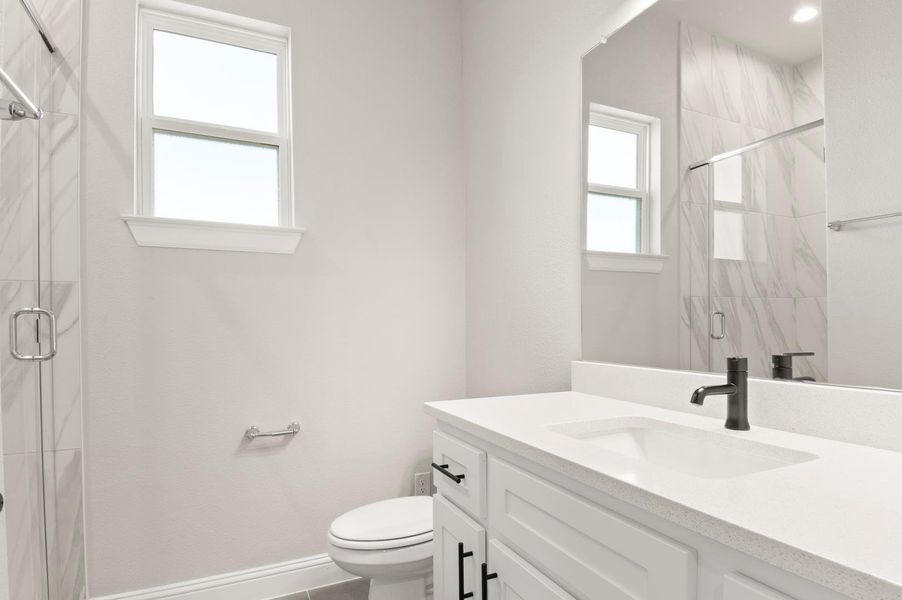 Bathroom featuring vanity, a marble finish shower, and tile patterned flooring Bathroom featuring vanity, a marble finish shower, and tile patterned flooring