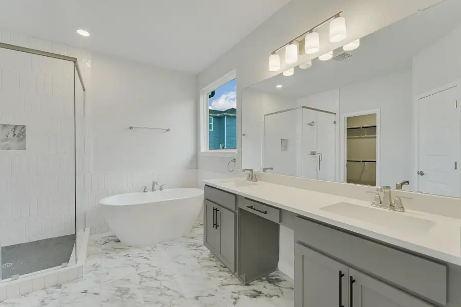 Bathroom featuring a stall shower, double vanity, a soaking tub, a spacious closet, and marble finish floors