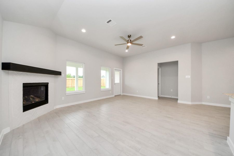 Family room flooded with natural light through the expansive windows.  The premium tile flooring adds a touch of luxury to the space, creating the perfect setting for relaxing moments and cherished gatherings with loved ones. Sample photo of completed home with similar floor plan. Actual colors and selections may vary.