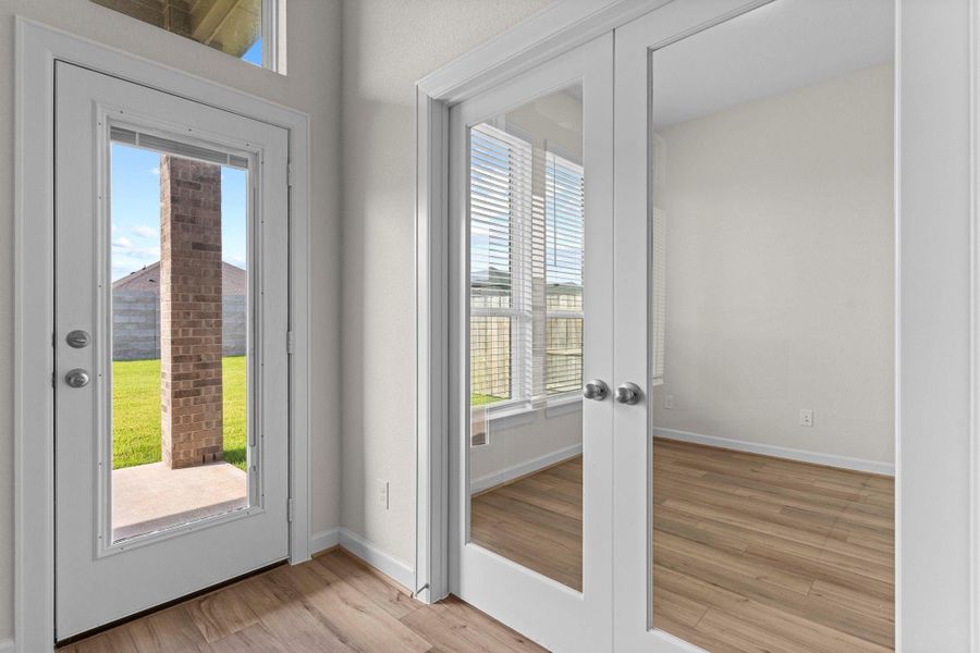 Bright private Home Office with French glass panel doors, wood-large plank tile looking flooring, and tall windows offering views of the backyard.