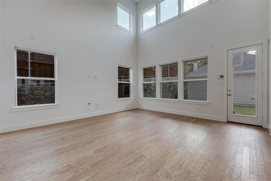 Unfurnished living room featuring a high ceiling, light hardwood / wood-style flooring, and plenty of natural light