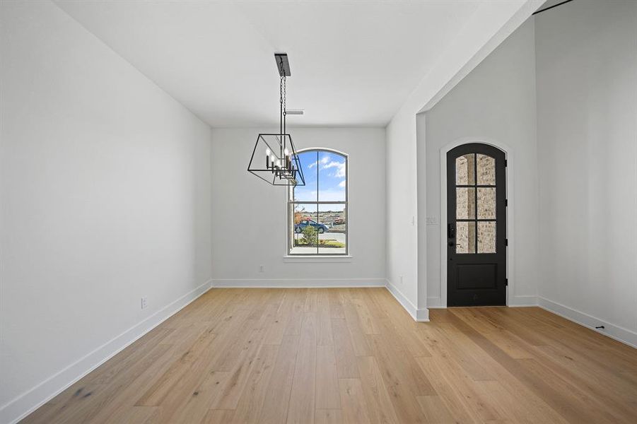 Entryway featuring light wood finished floors, a chandelier, and arched walkways
