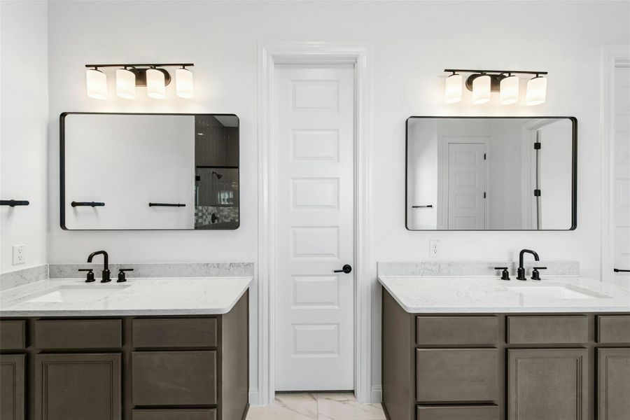 Bathroom featuring two vanities and light marble finish flooring