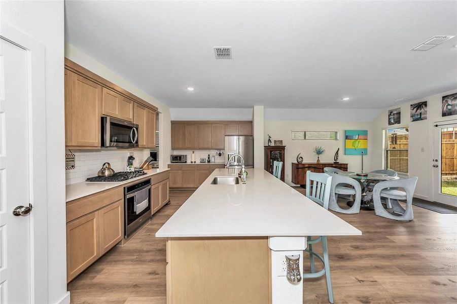 Kitchen featuring appliances with stainless steel finishes, an island with sink, light wood-type flooring, and sink