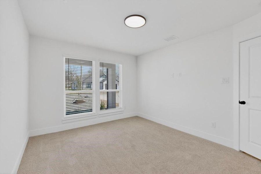 Office/bedroom featuring light colored carpet and baseboards