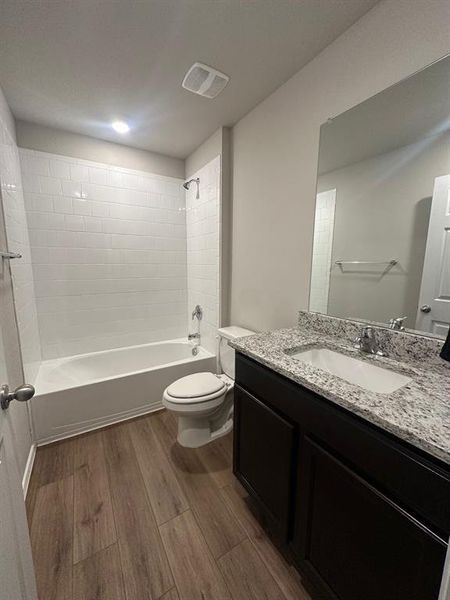 Bathroom featuring vanity, shower / bath combination, and dark wood finished floors