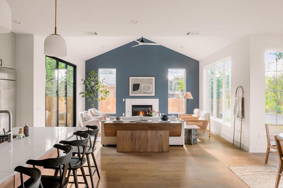 Living area featuring vaulted ceiling, light wood-style floors, a glass covered fireplace, and plenty of natural light Living area featuring vaulted ceiling, light wood-style floors, a glass covered fireplace, and plenty of natural light