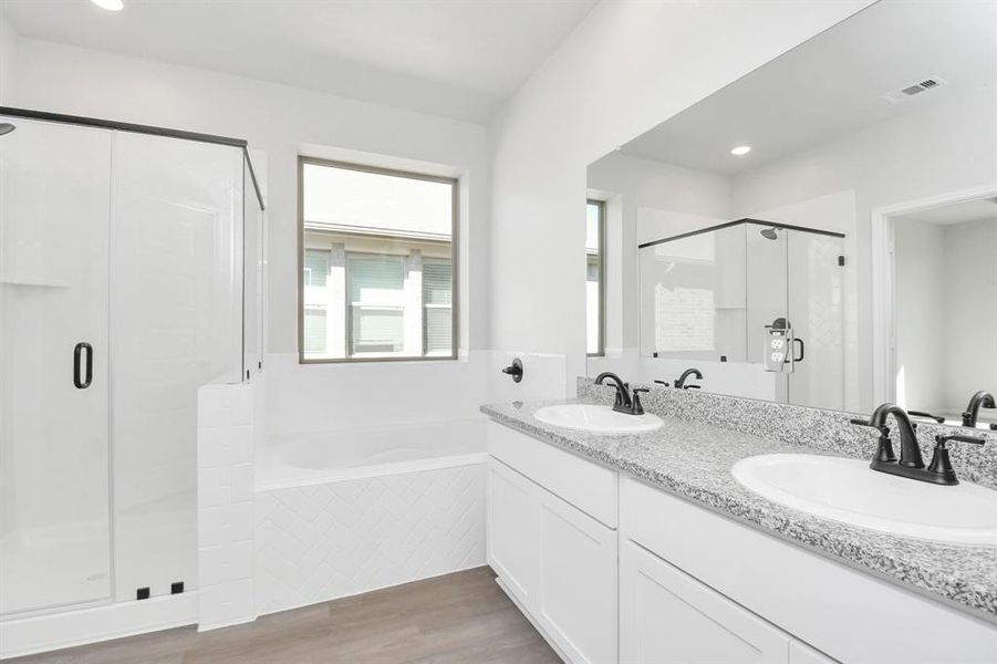 Escape to a spa-like oasis in this primary bathroom. Enjoy a walk-in showerwith tile surround, a separate garden tub with custom detailing, and an elegantvanity featuring light countertops, modern hardware, and beautiful recessed lights.Experience luxury and relaxation in every detail.