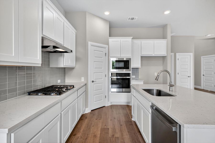 Kitchen featuring light stone counters, white cabinets, dark wood-style flooring, and recessed lighting Kitchen featuring light stone counters, white cabinets, dark wood-style flooring, and recessed lighting