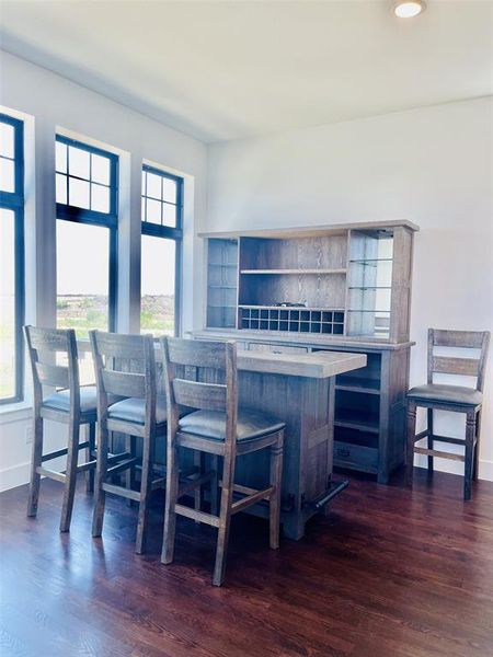Kitchen featuring open shelves, dark wood finished floors, a breakfast bar, recessed lighting, and light stone countertops Kitchen featuring open shelves, dark wood finished floors, a breakfast bar, recessed lighting, and light stone countertops