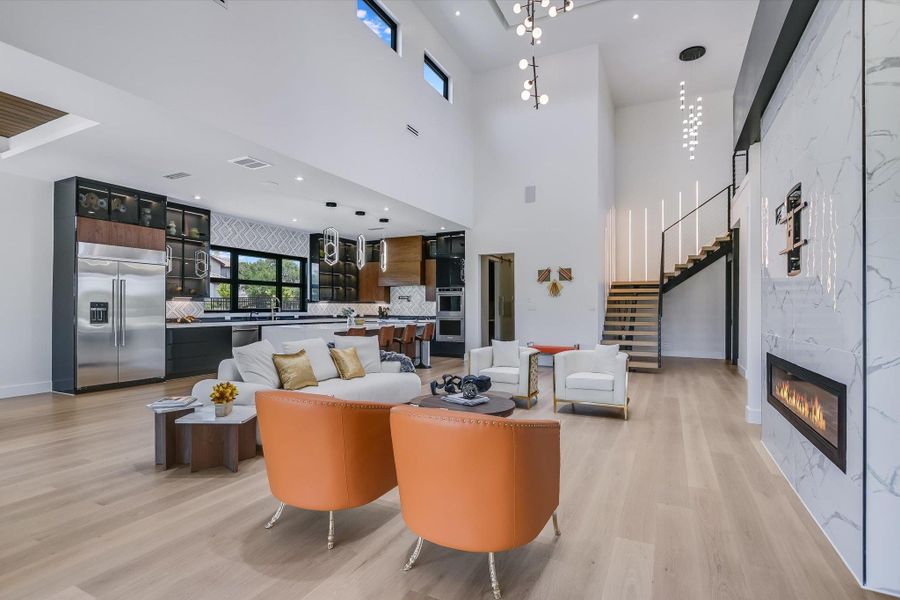 Living area with light wood finished floors, stairway, a large fireplace, and a towering ceiling Living area with light wood finished floors, stairway, a large fireplace, and a towering ceiling
