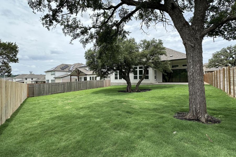 A spacious, newly landscaped yard with a privacy fence surrounds a modern home.