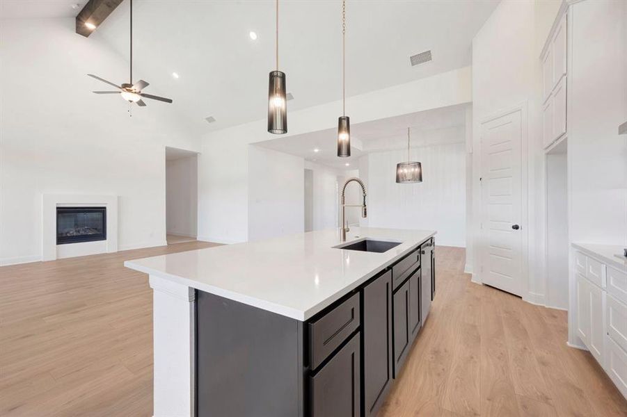 Kitchen island featuring a white countertop, dark cabinetry, and an integrated sink with a gooseneck faucet Kitchen island featuring a white countertop, dark cabinetry, and an integrated sink with a gooseneck faucet