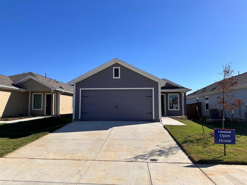 View of front of property featuring an attached garage, concrete driveway, and a front yard