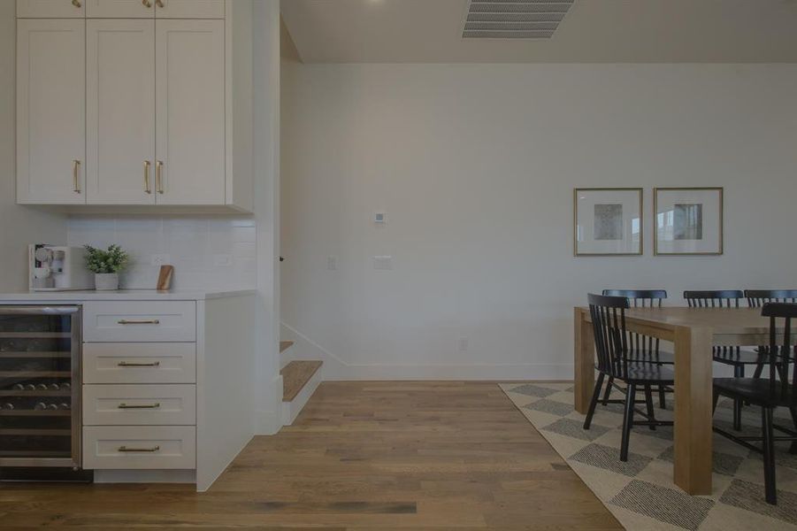 Dining space featuring wine cooler and light hardwood / wood-style flooring