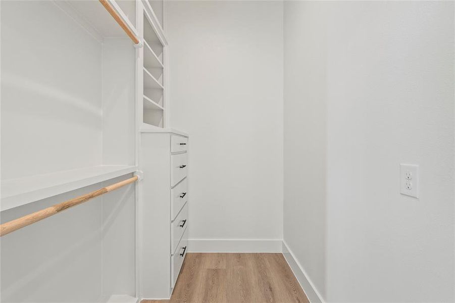 Walk in closet featuring light wood-style flooring Walk in closet featuring light wood-style flooring