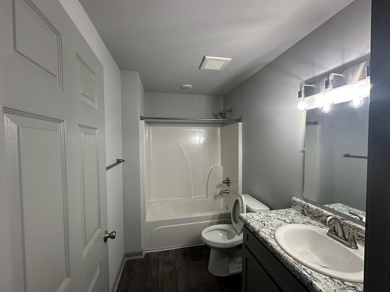 Full bathroom featuring toilet, shower / washtub combination, wood-type flooring, and oversized vanity