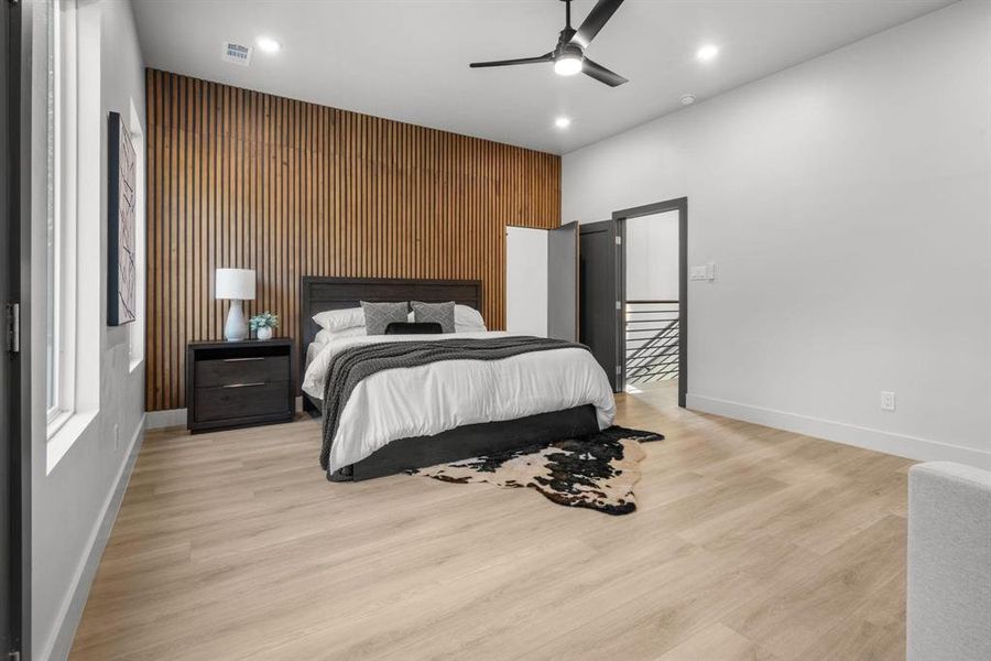 Bedroom featuring an accent wall, ceiling fan, wood walls, recessed lighting, and light wood-style floors