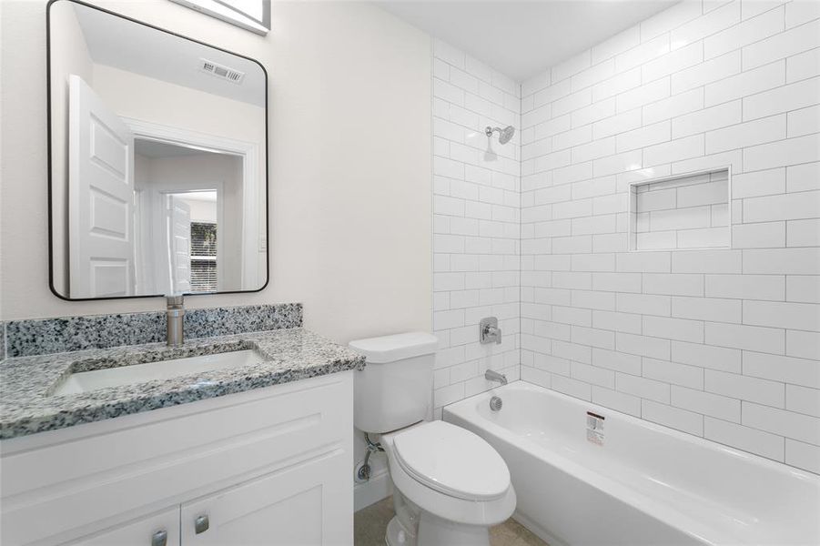 Full bathroom with tiled shower / bath, vanity, and toilet