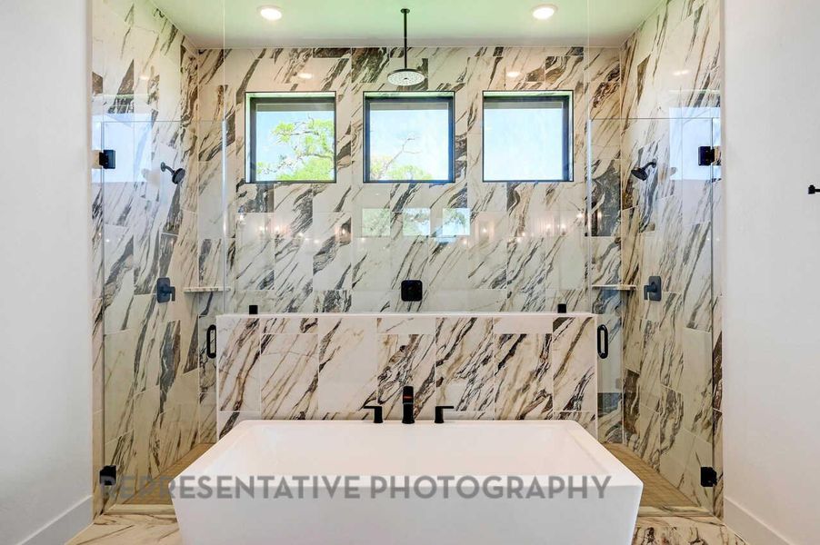 Bathroom with a marble finish shower and marble tiled flooring Bathroom with a marble finish shower and marble tiled flooring