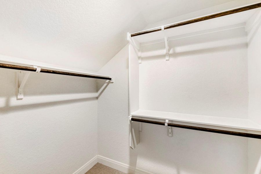 Walk in closet featuring vaulted ceiling and carpet flooring Walk in closet featuring vaulted ceiling and carpet flooring