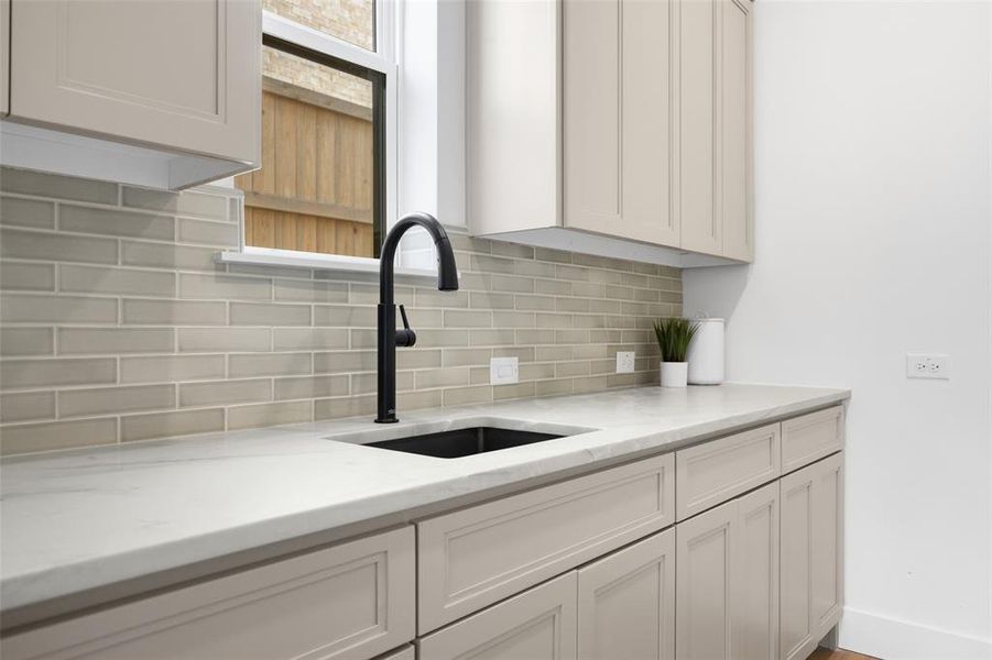 Kitchen featuring backsplash and light stone counters Kitchen featuring backsplash and light stone counters