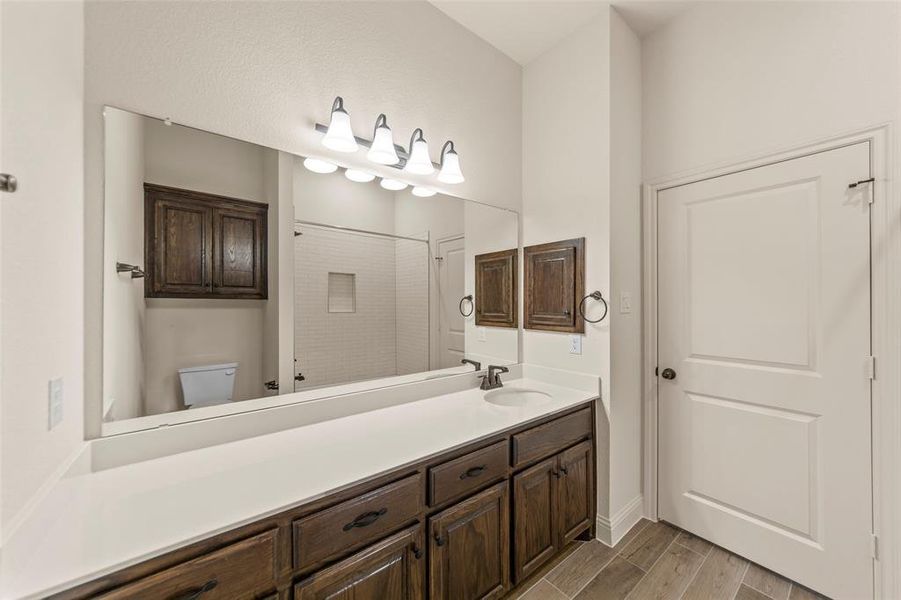 Full bathroom with vanity, wood finish floors, and a shower Full bathroom with vanity, wood finish floors, and a shower