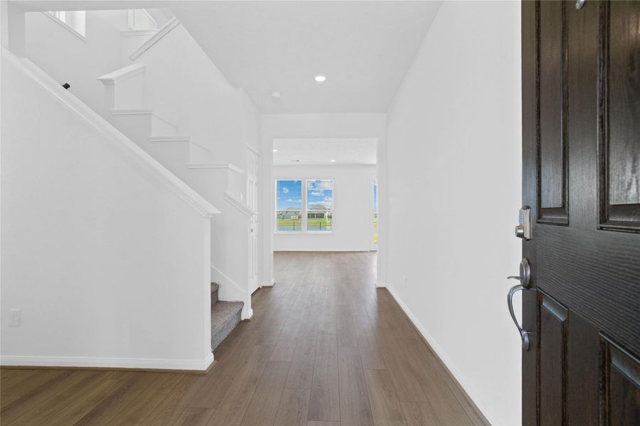 Upon entering, you find a lovely corridor showcasing custom paint, beautiful vinyl plank flooring, high ceilings, and ample lighting. Upon entering, you find a lovely corridor showcasing custom paint, beautiful vinyl plank flooring, high ceilings, and ample lighting.