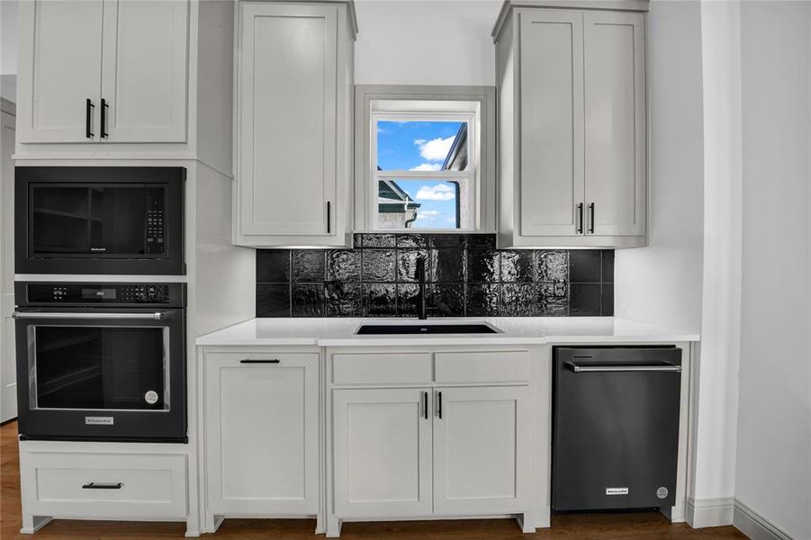 Kitchen featuring white cabinetry, stainless steel oven, tasteful backsplash, and sink