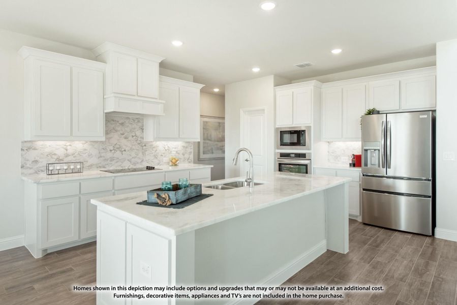 Kitchen with white cabinets, large island, marble backsplash, and stainless steel appliances on wood-look tile floors