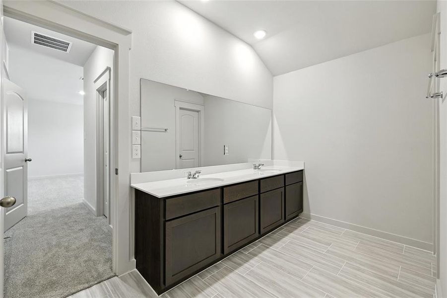 Full bathroom featuring double vanity and vaulted ceiling Full bathroom featuring double vanity and vaulted ceiling