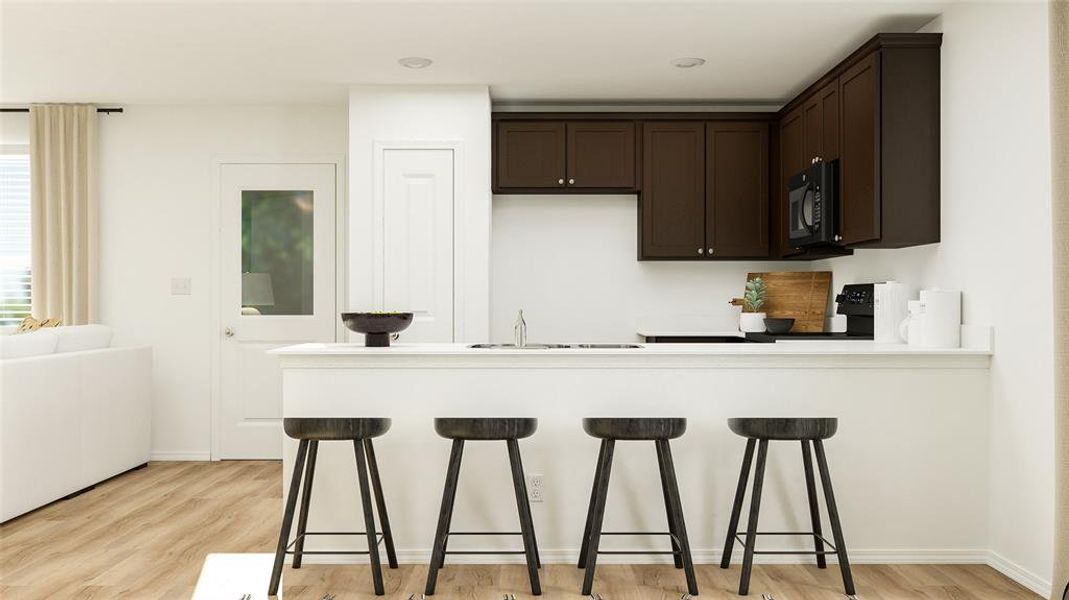 Kitchen featuring range, dark brown cabinetry, black microwave, and a kitchen bar Kitchen featuring range, dark brown cabinetry, black microwave, and a kitchen bar