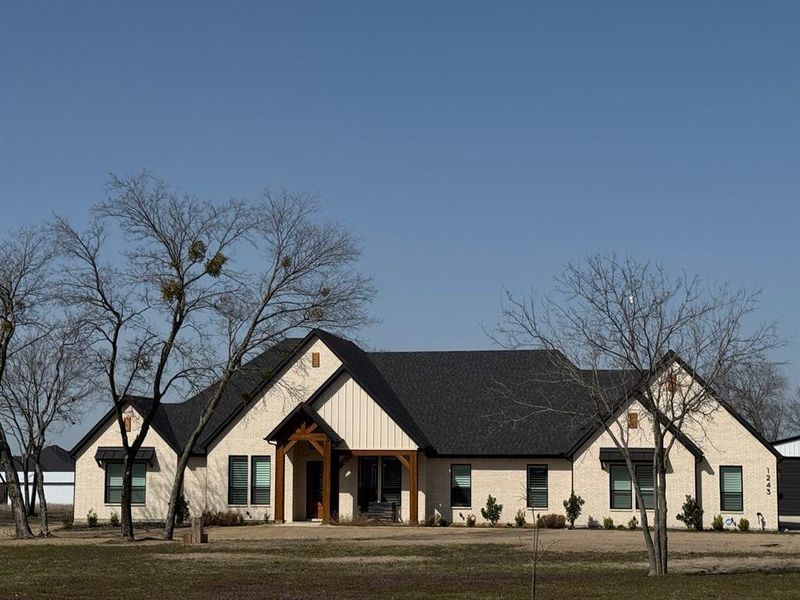 View of front facade with a front lawn, board and batten siding, and roof with shingles