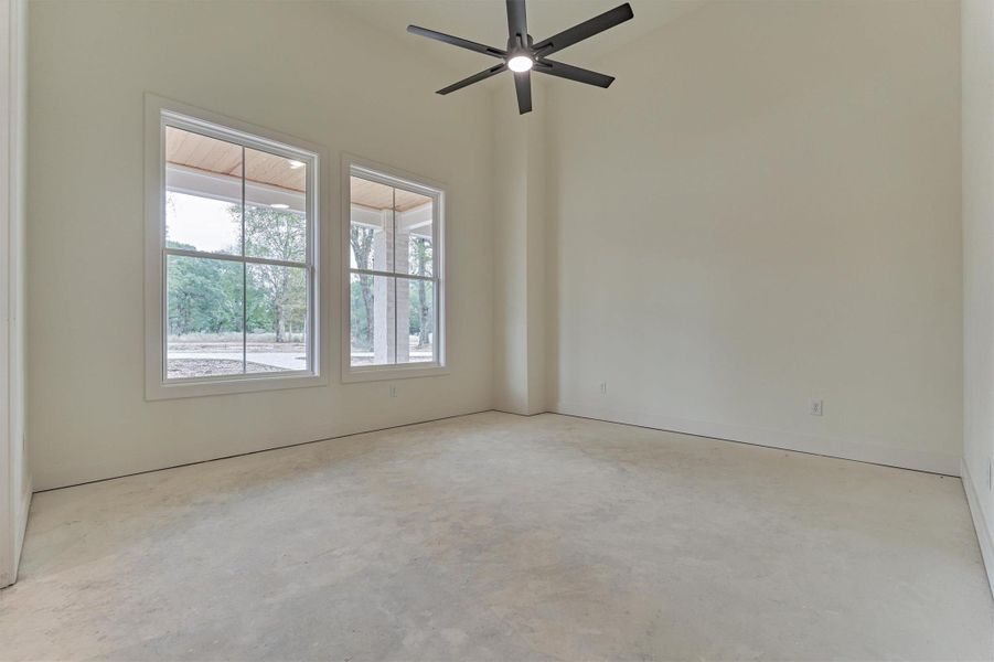 Bright bedroom with soaring ceilings, oversized windows, and peaceful views of the surrounding property.