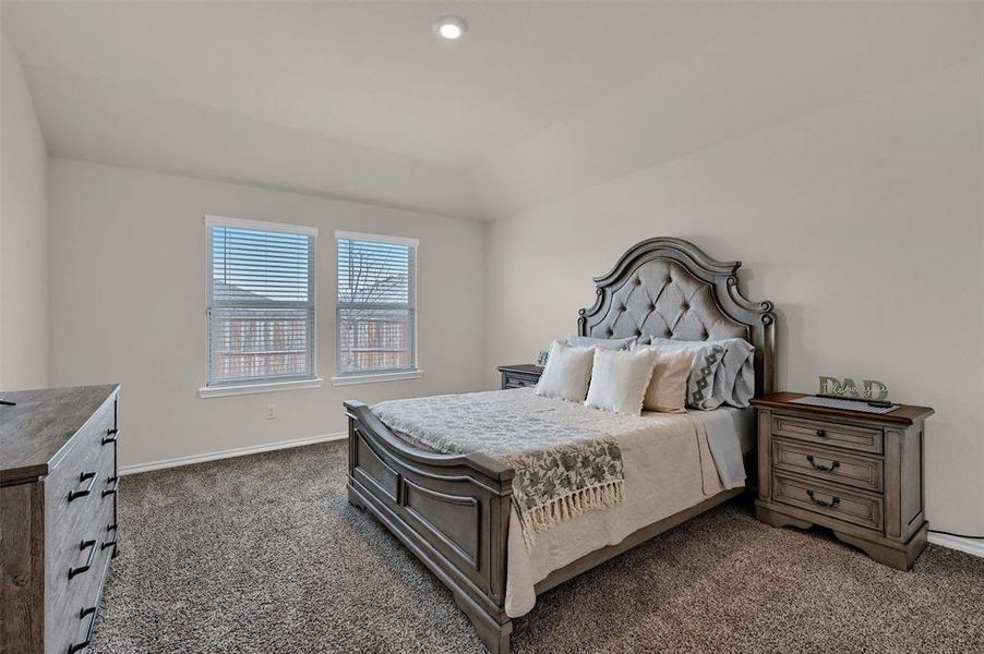 Bedroom with baseboards, vaulted ceiling, and dark colored carpet