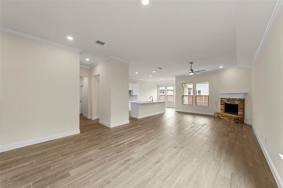 Spacious living area featuring wood-finish flooring, recessed lighting, and a brick fireplace with a white mantel