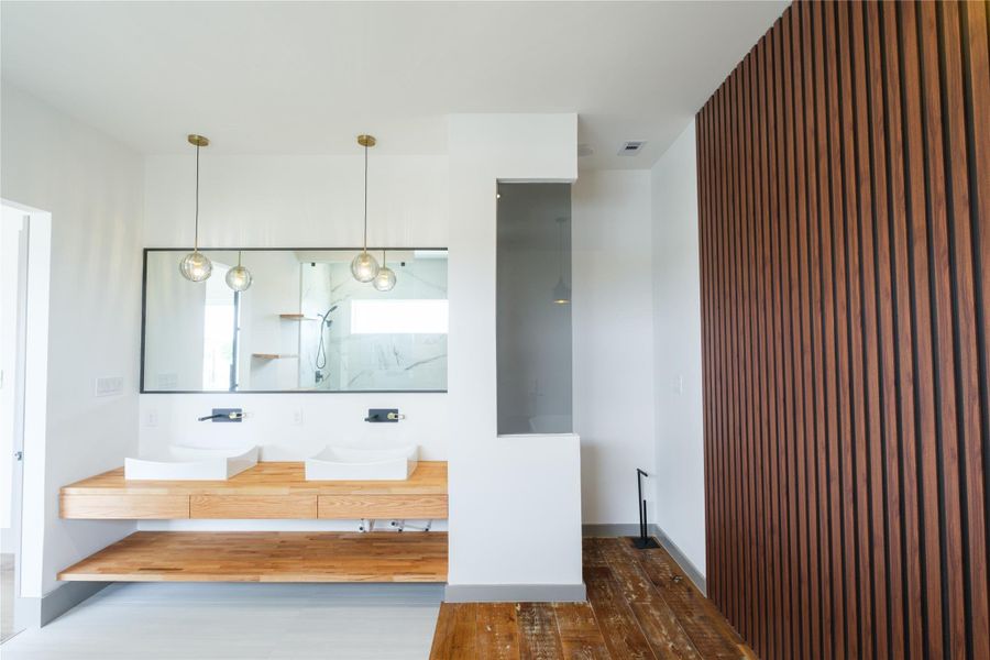 Representative Primary Bath View 2 (Design selections and colors may vary): A custom wood vanity with dual vessel sinks, floating shelves, and built-in drawers adds another layer of sophistication and practicality to this beautifully crafted space.