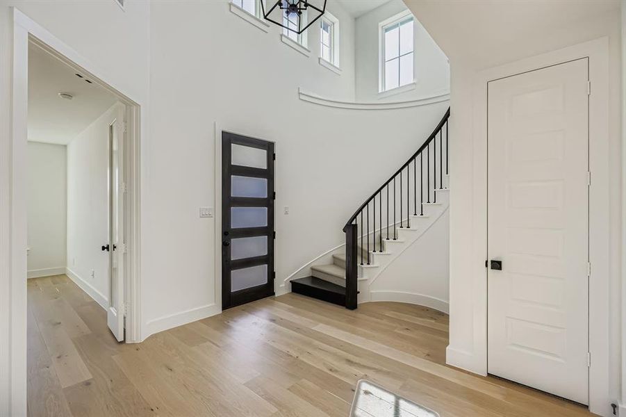 Entryway with light wood finished floors, stairway, and a towering ceiling