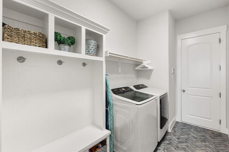 Laundry room featuring brick flooring and washer and clothes dryer