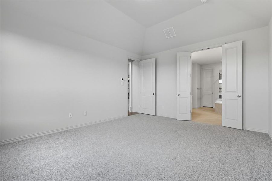 Unfurnished bedroom with light carpet and vaulted ceiling Unfurnished bedroom with light carpet and vaulted ceiling