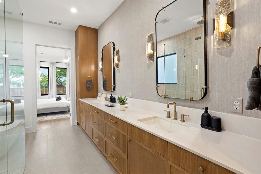 Double vanity featuring light wood-finish cabinetry, white countertops, and brass-finish fixtures