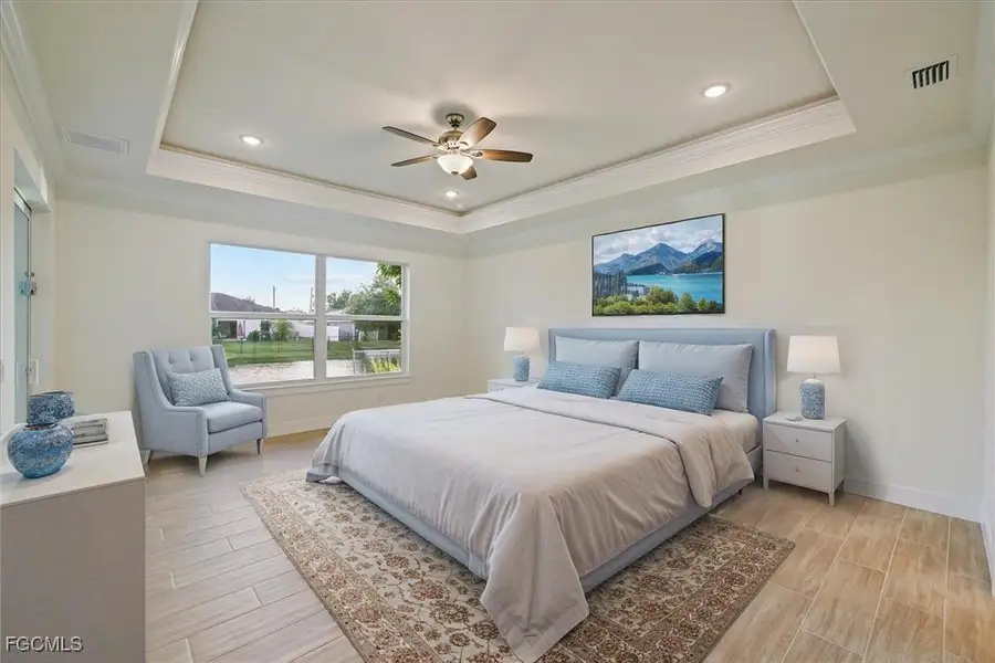Bedroom with crown molding, wood tiled floors, a tray ceiling, ceiling fan, and recessed lighting