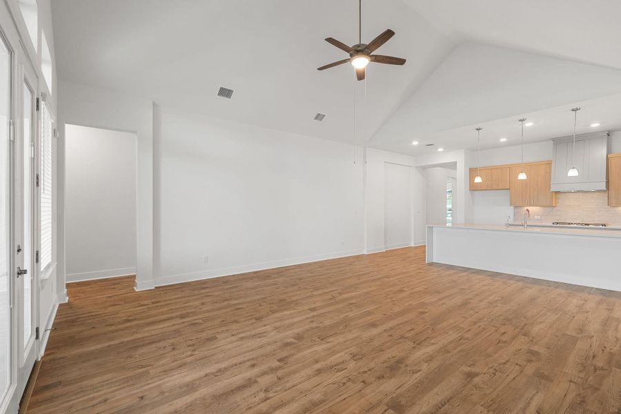 An open concept living area transitions effortlessly into a contemporary kitchen, illuminated by recessed lighting and a vaulted ceiling.