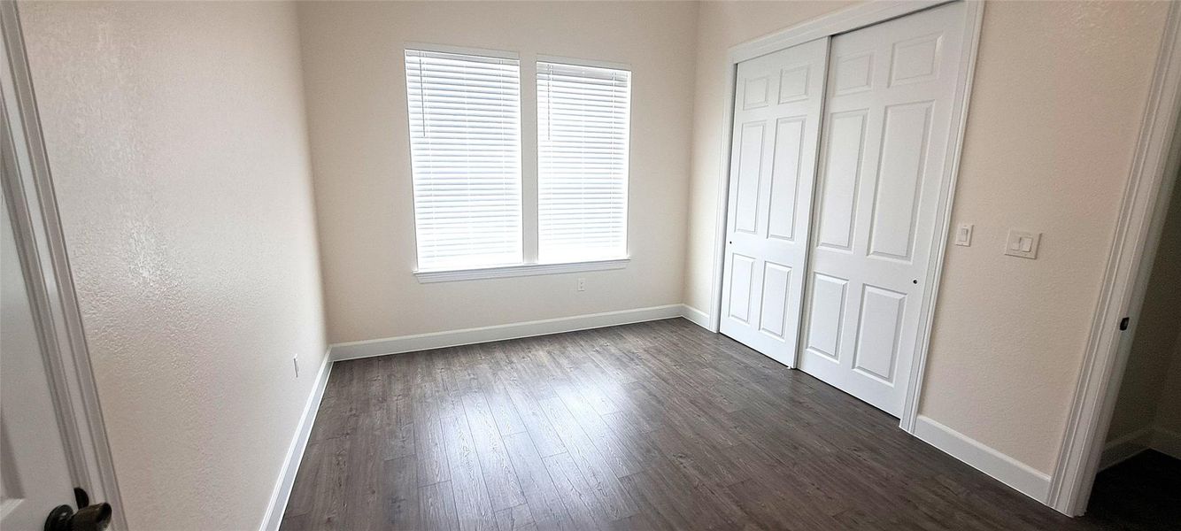 Unfurnished bedroom with a closet and dark wood finished floors
