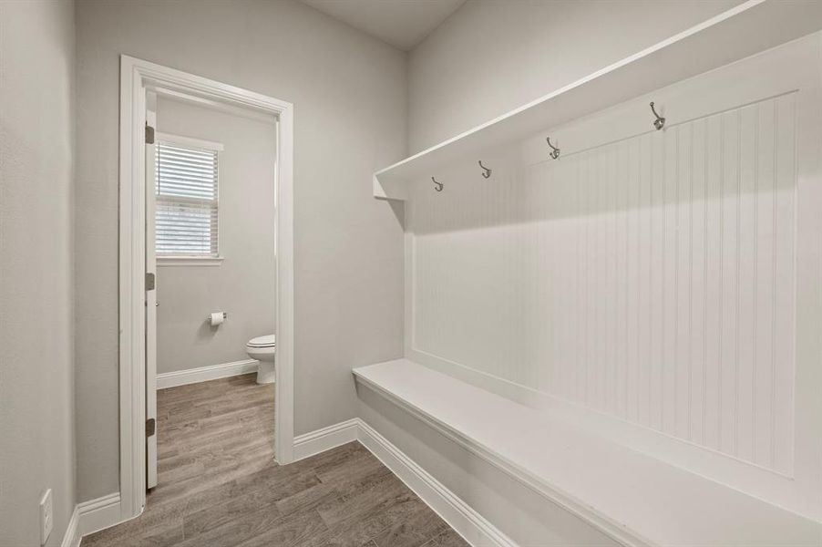 Mudroom area with built-in bench and hooks, conveniently located near the powder bath.